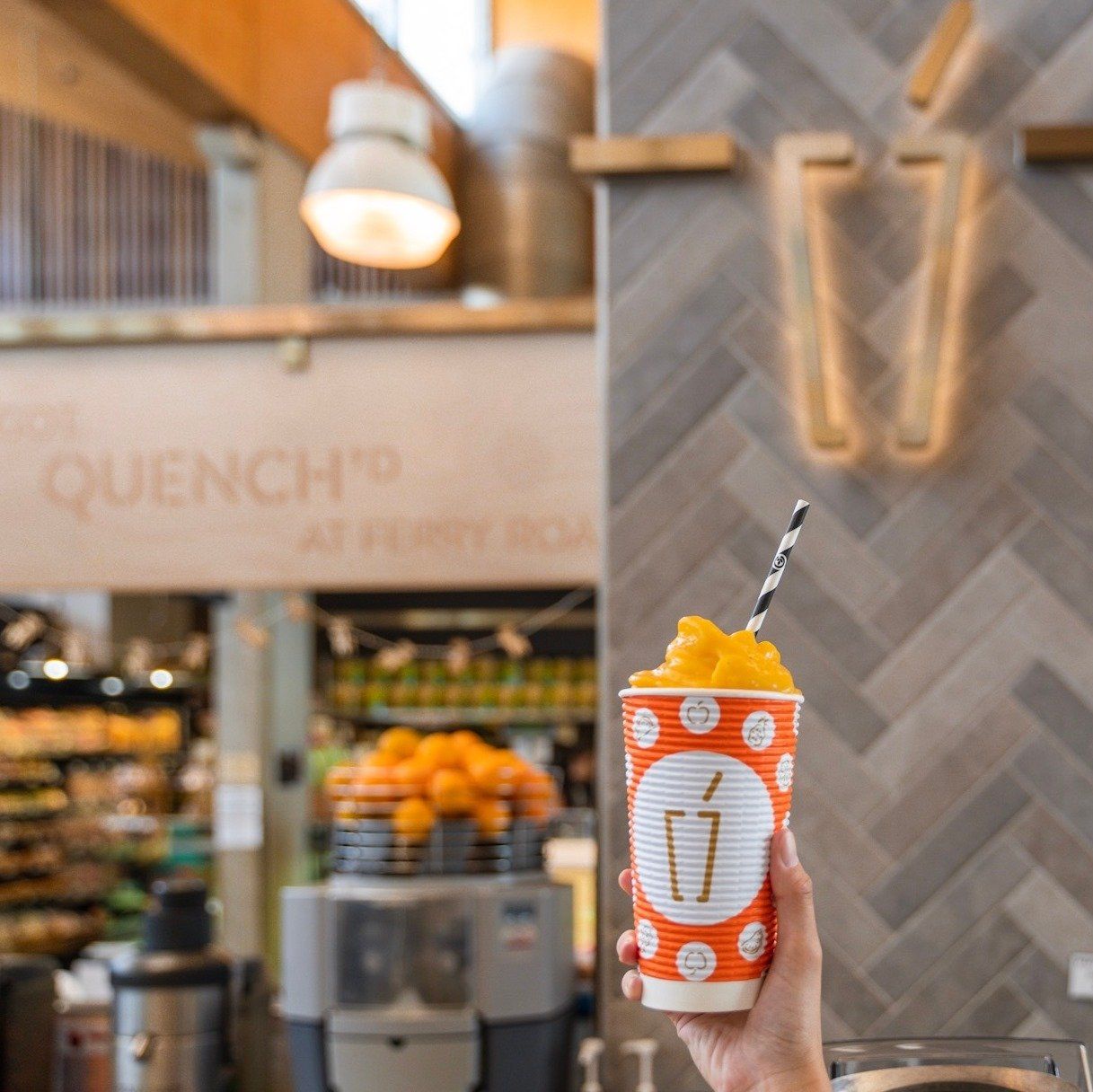 Hand Holding an Orange Smoothie In Front of Quench Juice Bar — Quench Juice Bar in Fortitude Valley, QLD