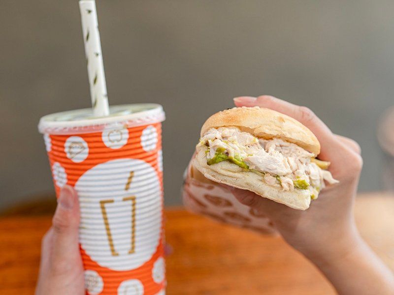 Hands Holding Juice and Chicken & Avocado Focaccia — Quench Juice Bar in Fortitude Valley, QLD