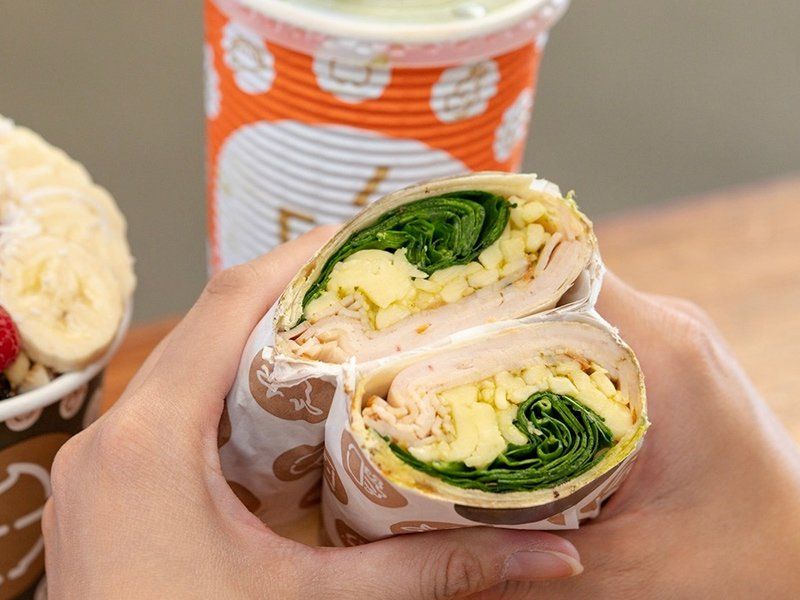 Person Holding Turkey, Cheese & Spinach Wrap — Quench Juice Bar in Fortitude Valley, QLD