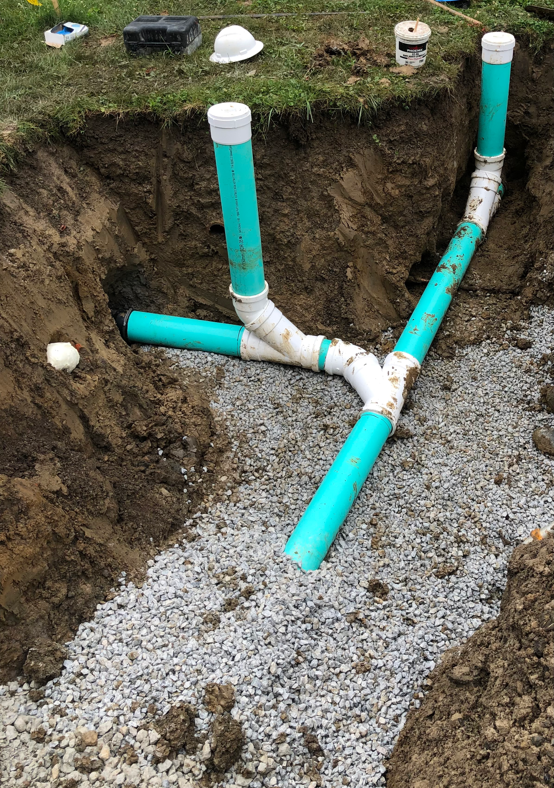 A drain pipe is being installed in a hole in the ground.