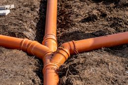 A bunch of orange pipes are connected to each other in the dirt.