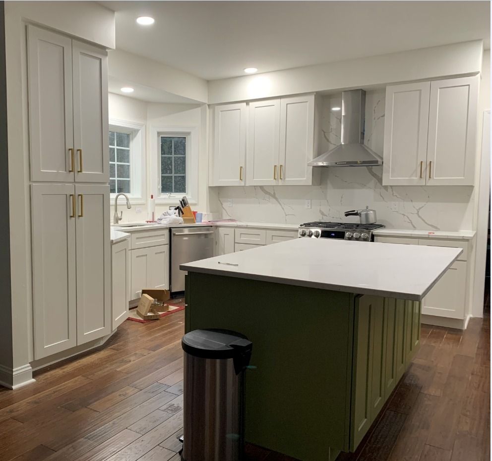 A modern kitchen with white cabinets, marble-look backsplash, and a green 