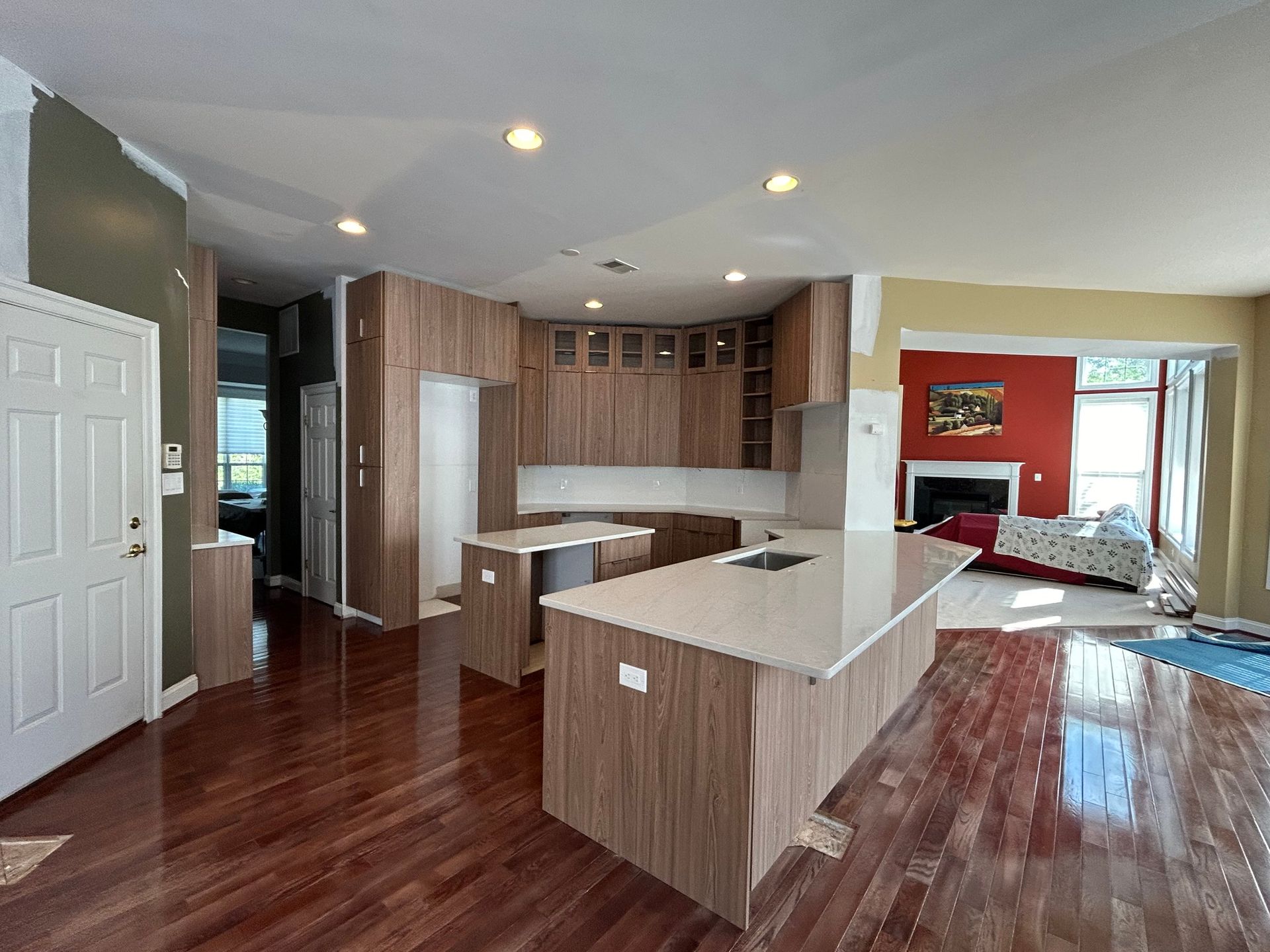 A modern kitchen with wood cabinets and white countertops. Islands with the same finishes are in the center of the room.
