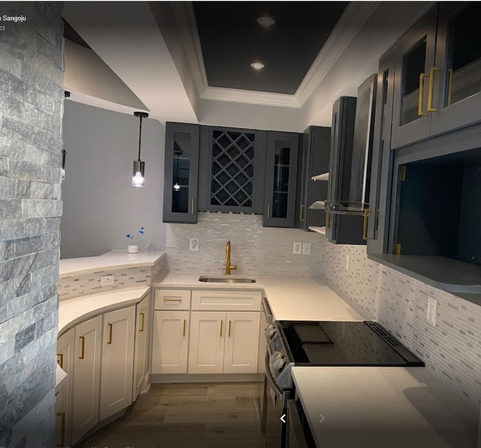 Gray and white modern kitchen with curved countertops, white and gold cabinetry, and a dark gray ceiling.