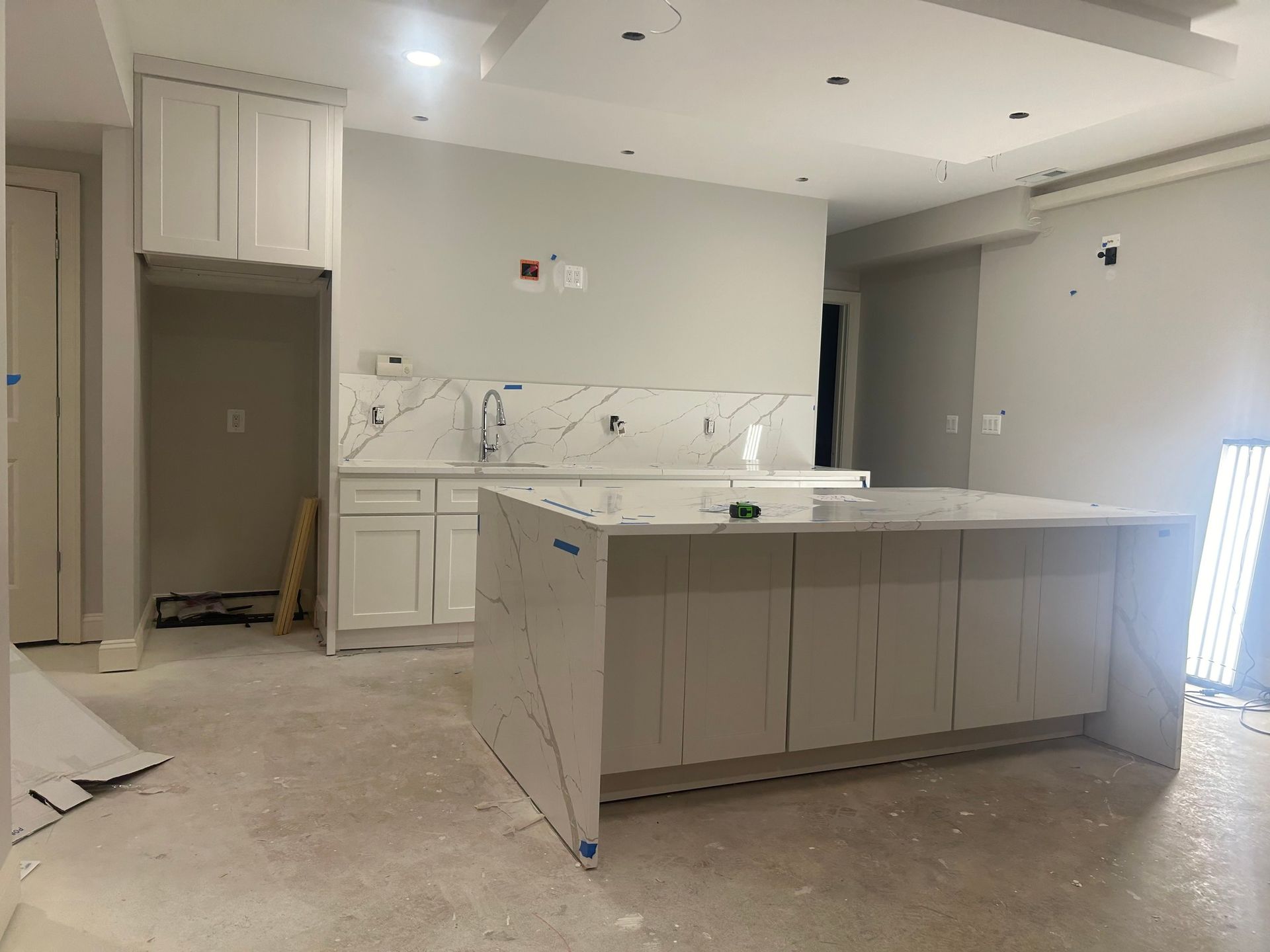 A newly constructed kitchen with white cabinets, countertops, and a large 