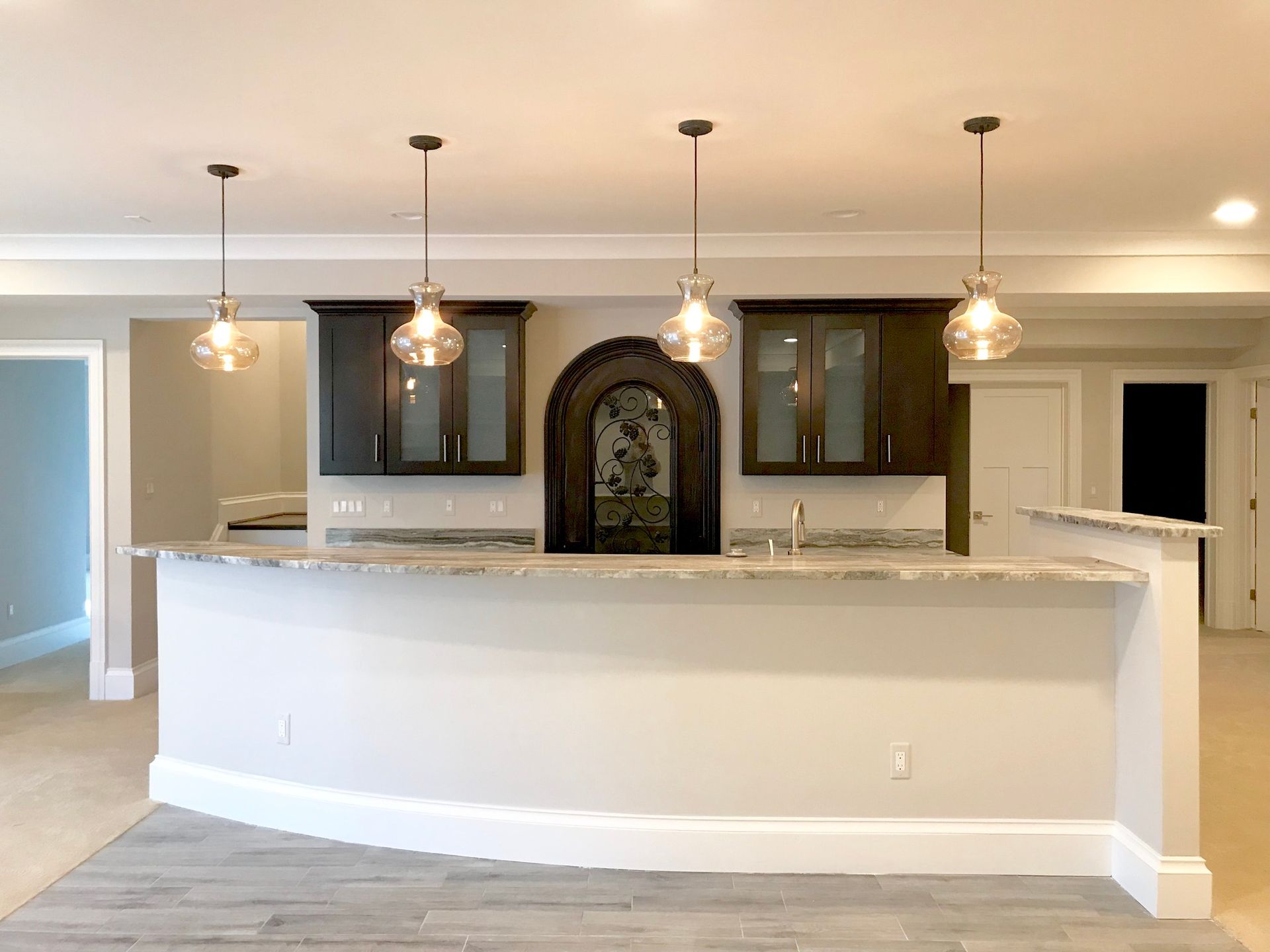A newly renovated home bar with a curved white counter, dark cabinets, and 