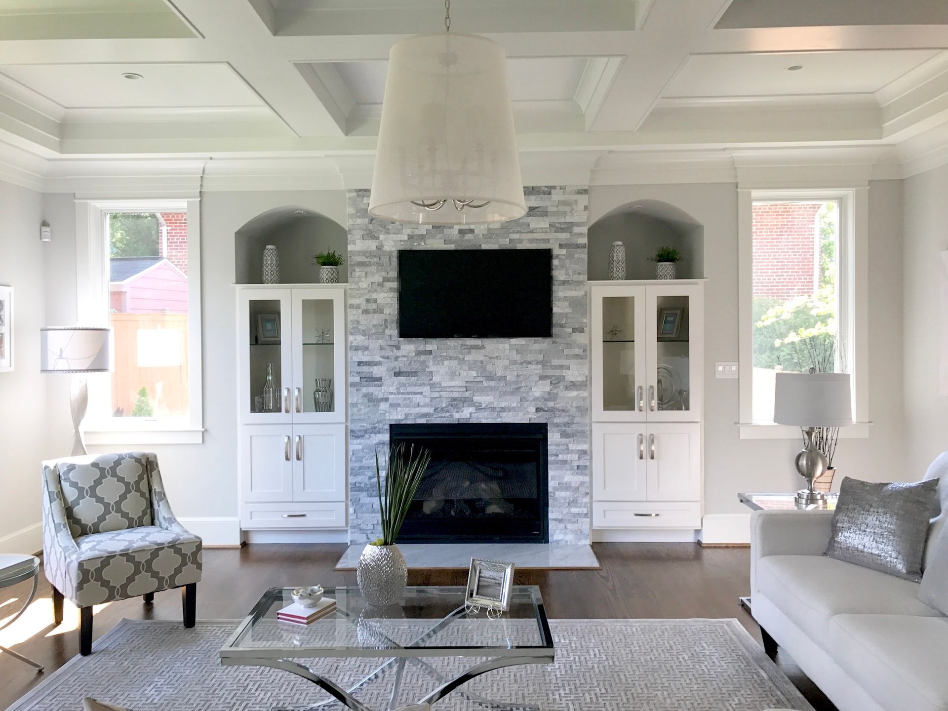 Living room with a fireplace, TV, and built-in cabinets. White walls, gray stone