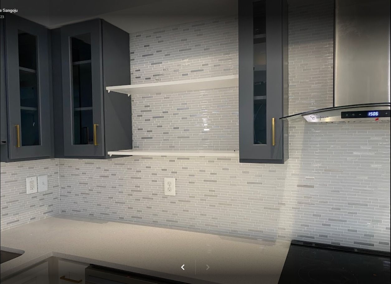 Kitchen with dark gray cabinets, white tiled backsplash, and open shelving.