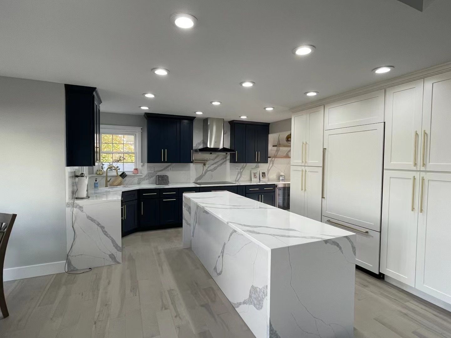 Modern kitchen with navy blue and white cabinets, quartz countertops, and a large island.