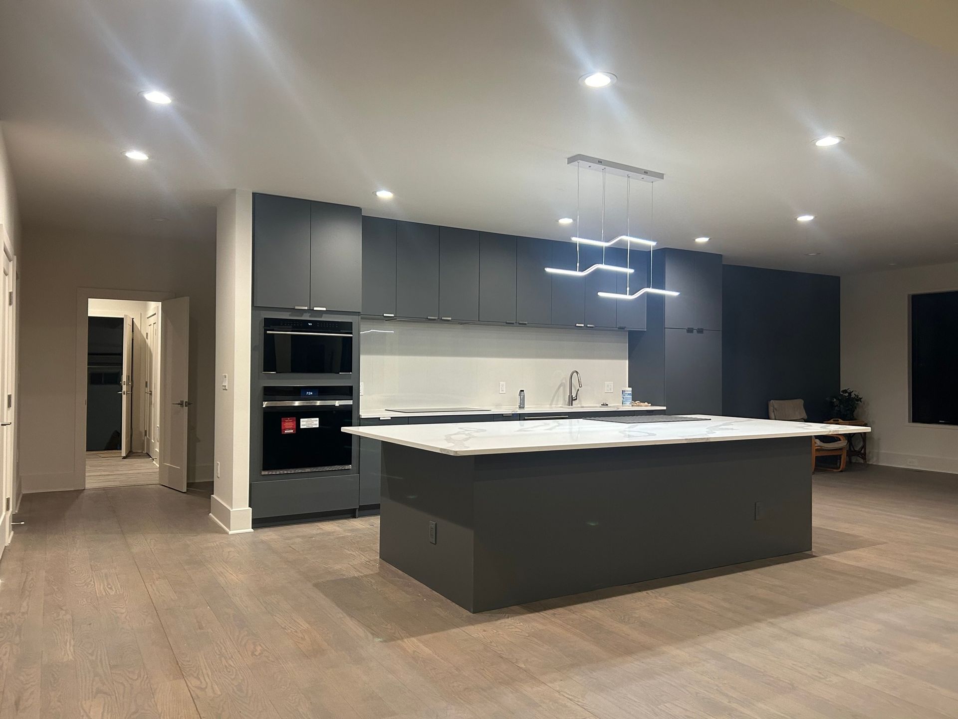 Modern kitchen with gray cabinets and island, marble countertops, and light 