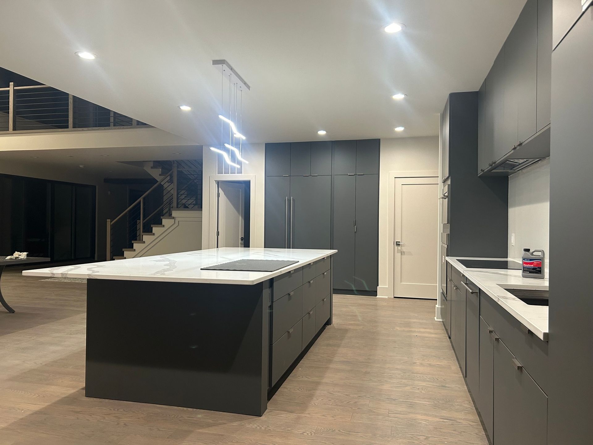Modern kitchen with dark gray cabinetry, large island with marble countertop, a