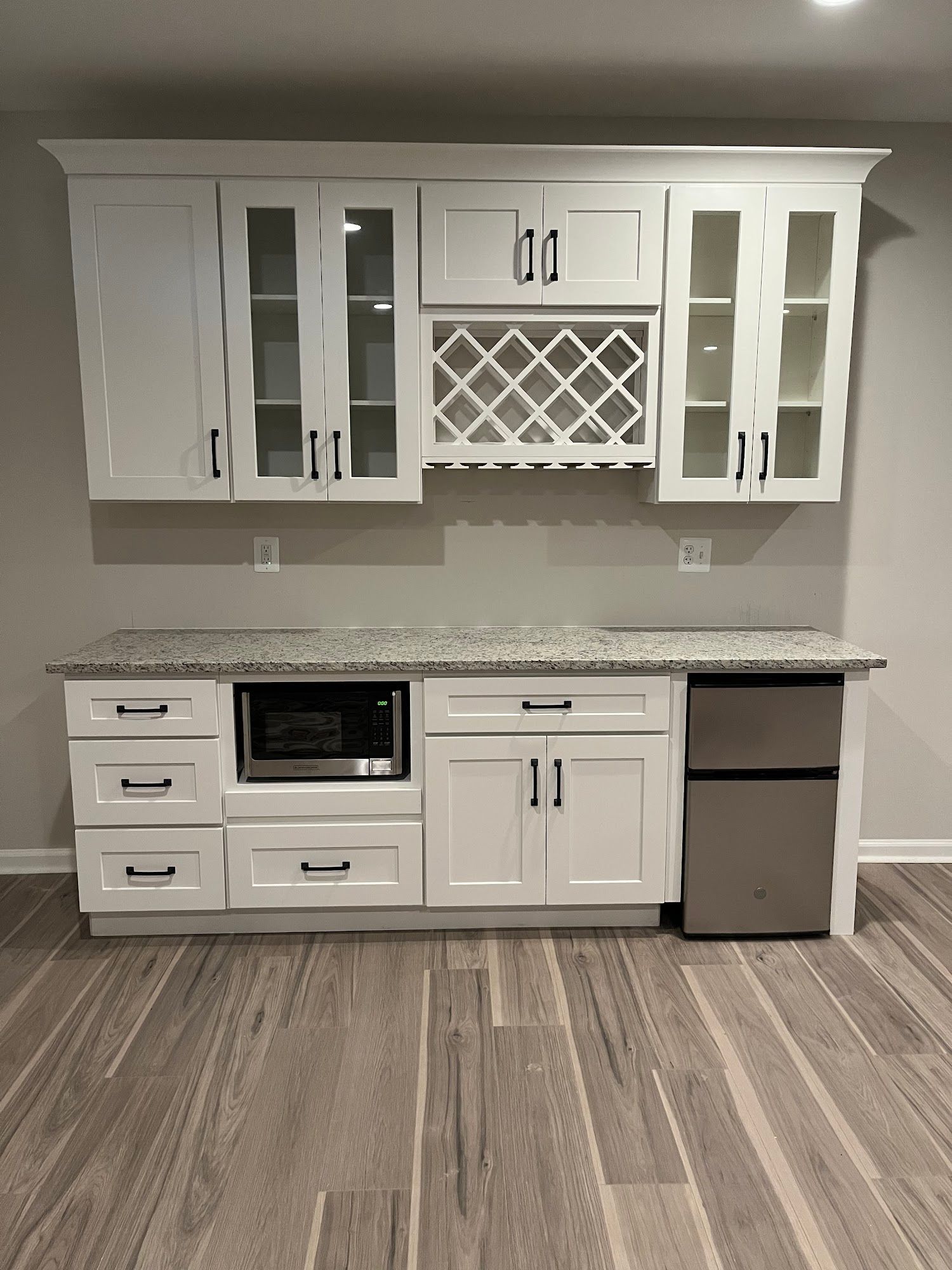White kitchen cabinets with granite countertop, microwave, and wine fri