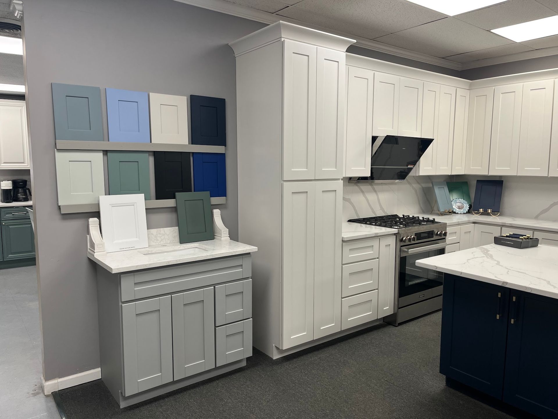 Kitchen showroom with cabinet displays. White and gray cabinets are featured, along with paint color samples on the wall.