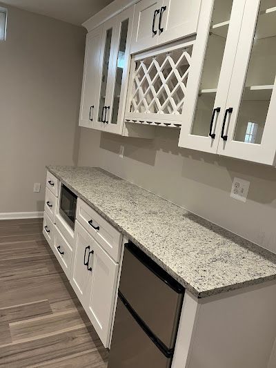 White cabinets with a granite countertop and stainless steel appliances. A wine rack is built into the upper cabinets.