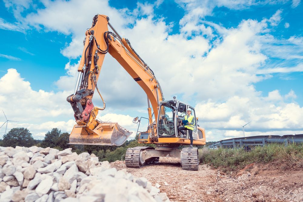 A yellow excavator is moving rocks on a construction site.