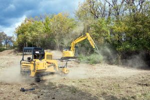 A bulldozer and an excavator are working in a dirt field.