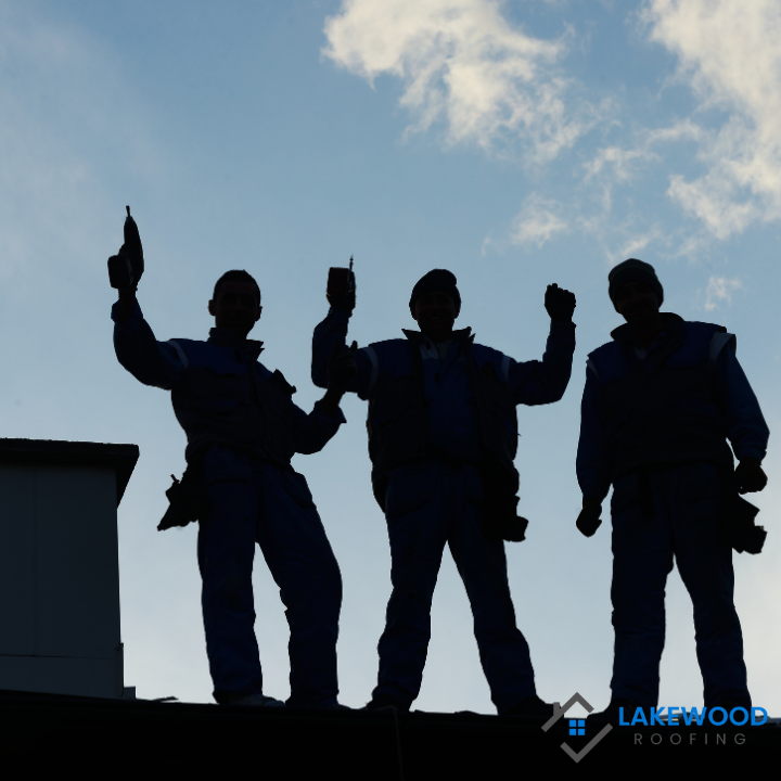 Three men standing on top of a building with a lakewood roofing logo in the corner