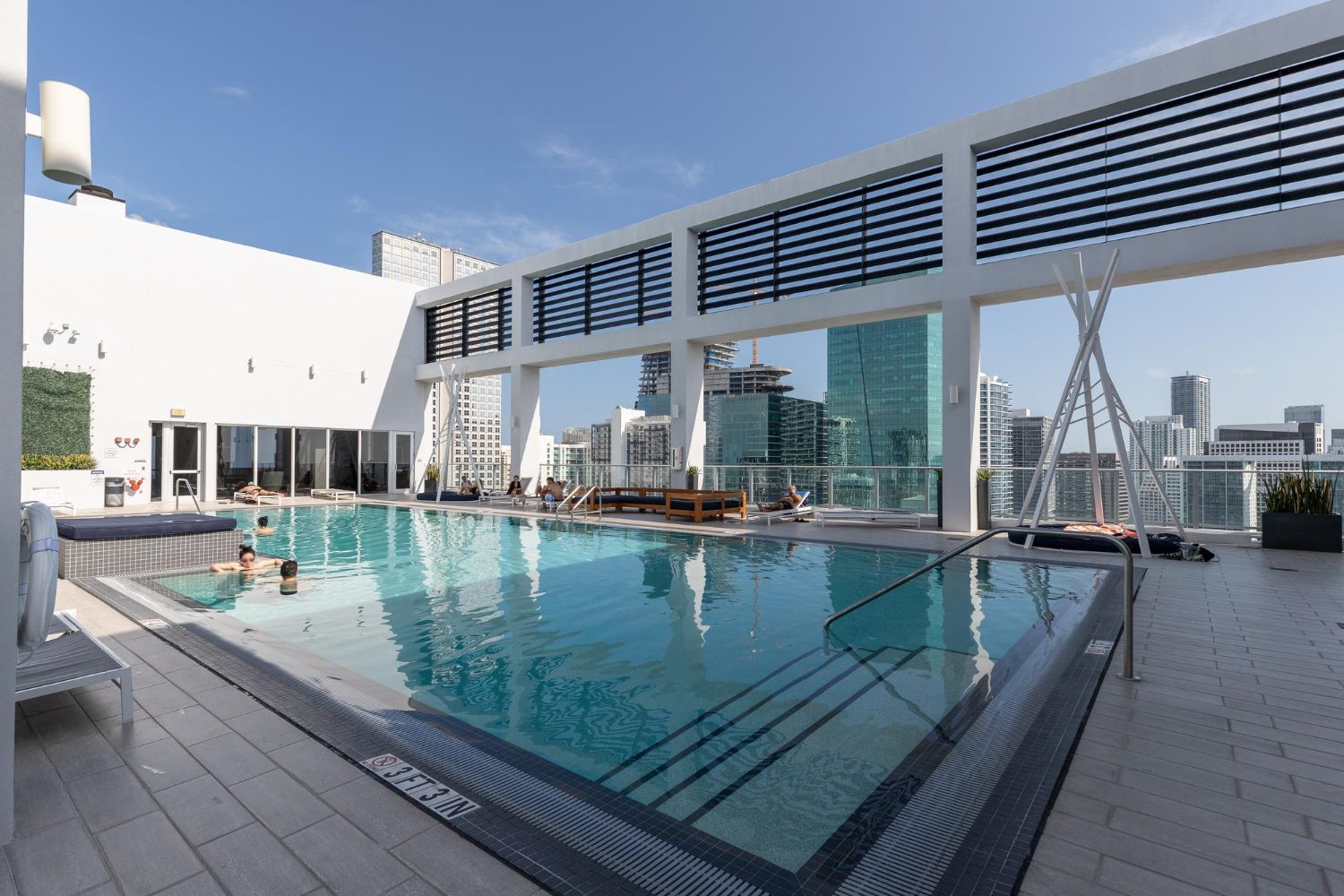 A large swimming pool on top of a building with a city in the background.