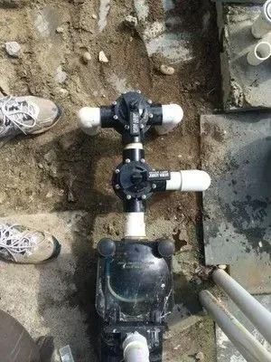 A person is working on a swimming pool pump in the dirt.