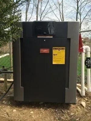 A large black box is sitting in the dirt next to a fence.