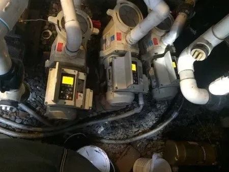 A bunch of pumps are sitting on top of a pile of pipes.