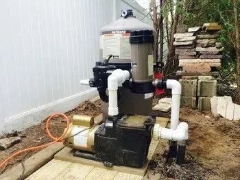 A swimming pool filter and pump are sitting on a wooden deck.
