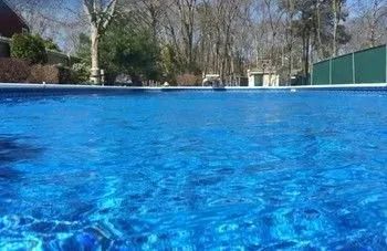 A large swimming pool filled with blue water and trees in the background.