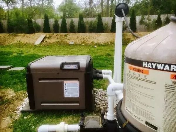 A haywar pool heater is sitting next to a haywar filter