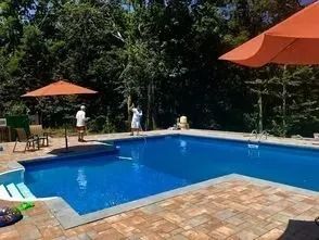 A large swimming pool surrounded by trees and umbrellas.