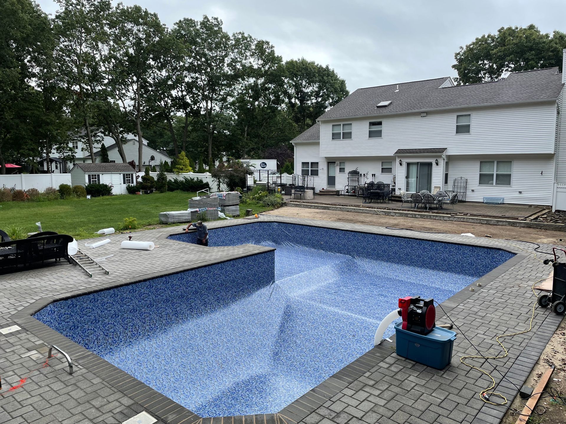 A man is working on a deck next to a swimming pool.