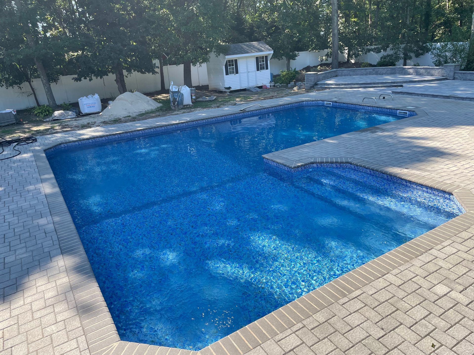 A man in a red shirt is working on a swimming pool.