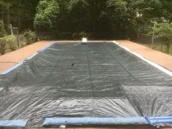 A large swimming pool with a black cover on it.