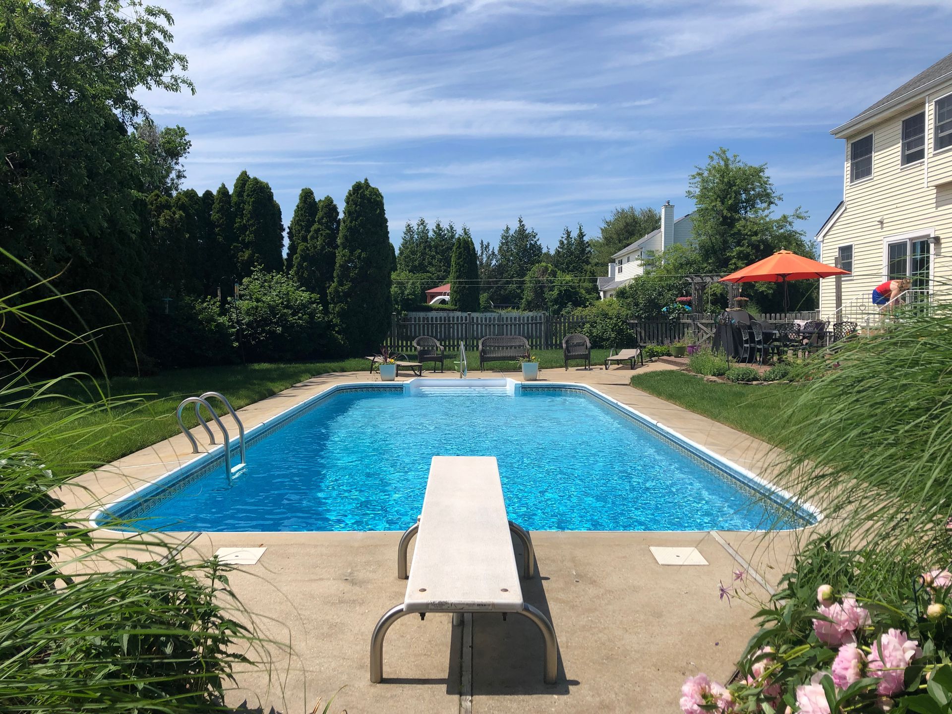 A person is holding a box of chemicals in front of a swimming pool.