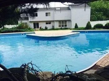 A large swimming pool with a house in the background.