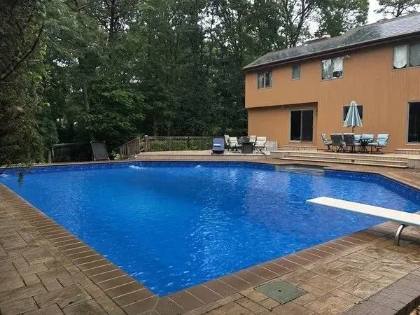 A large swimming pool with a diving board in front of a house.