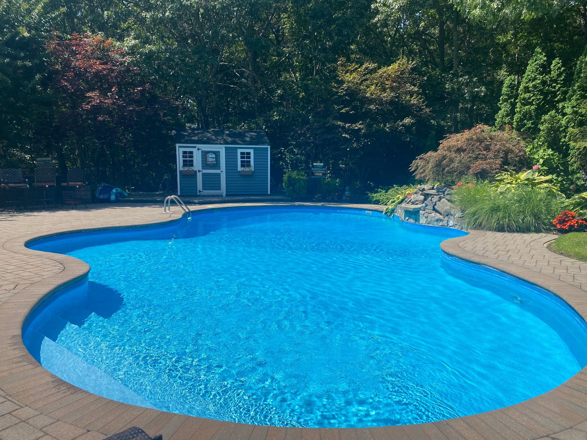 A row of blue umbrellas and lounge chairs next to a swimming pool.