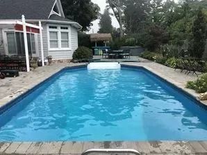 There is a large swimming pool in the backyard of a house.