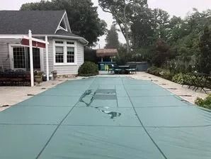 A large swimming pool with a green cover on it in front of a house.