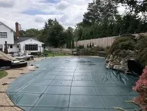 A large swimming pool is covered with a green cover.