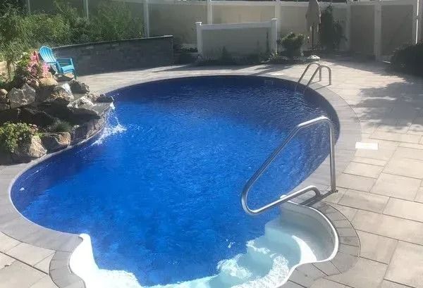 A small swimming pool with stairs leading to it is sitting on top of a patio.