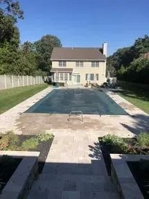 There is a large swimming pool in the backyard of a house.