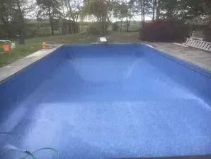 A large blue swimming pool with a ladder in the background.