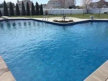 A large swimming pool filled with blue water in a backyard.