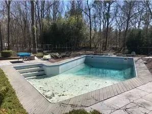 A person is cleaning a swimming pool with a vacuum cleaner.