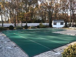 A large green tarp is covering a swimming pool.