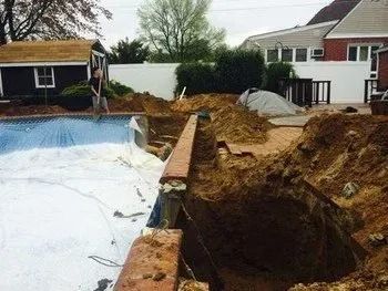 A swimming pool is being built in the backyard of a house.