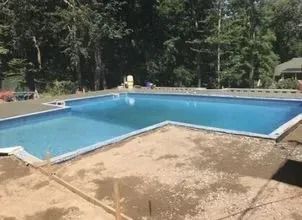 A large swimming pool is being built in the backyard of a house.