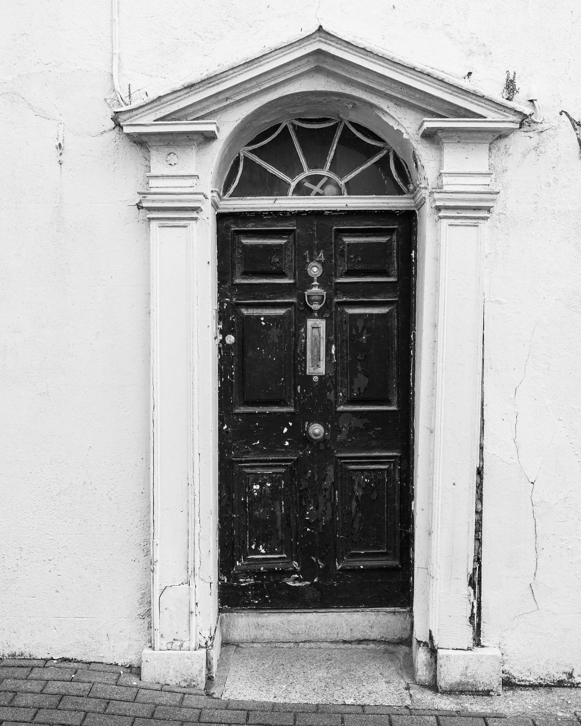 A black and white photo of a door on a white building