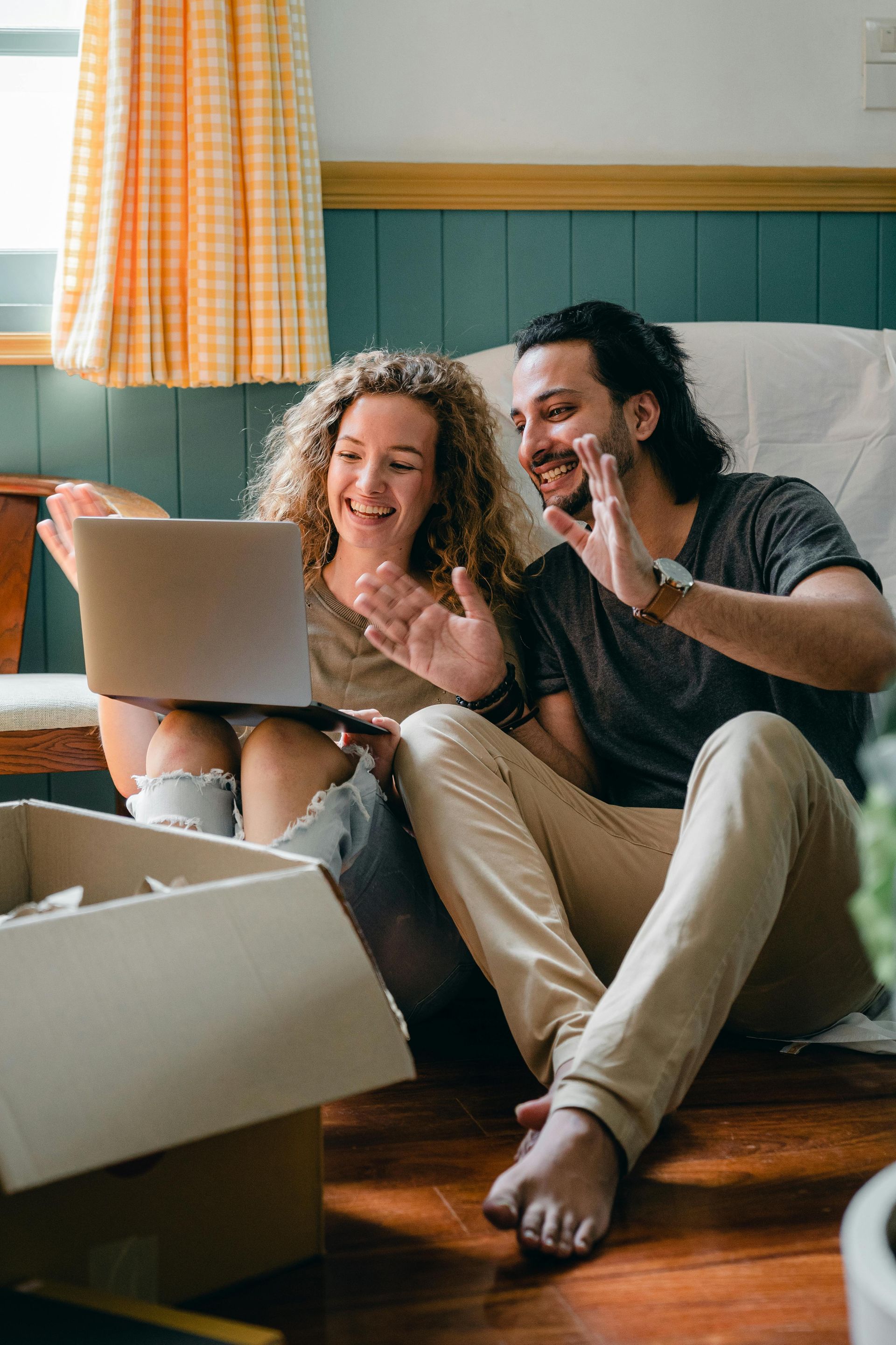 A man and a woman are sitting on the floor looking at a laptop.