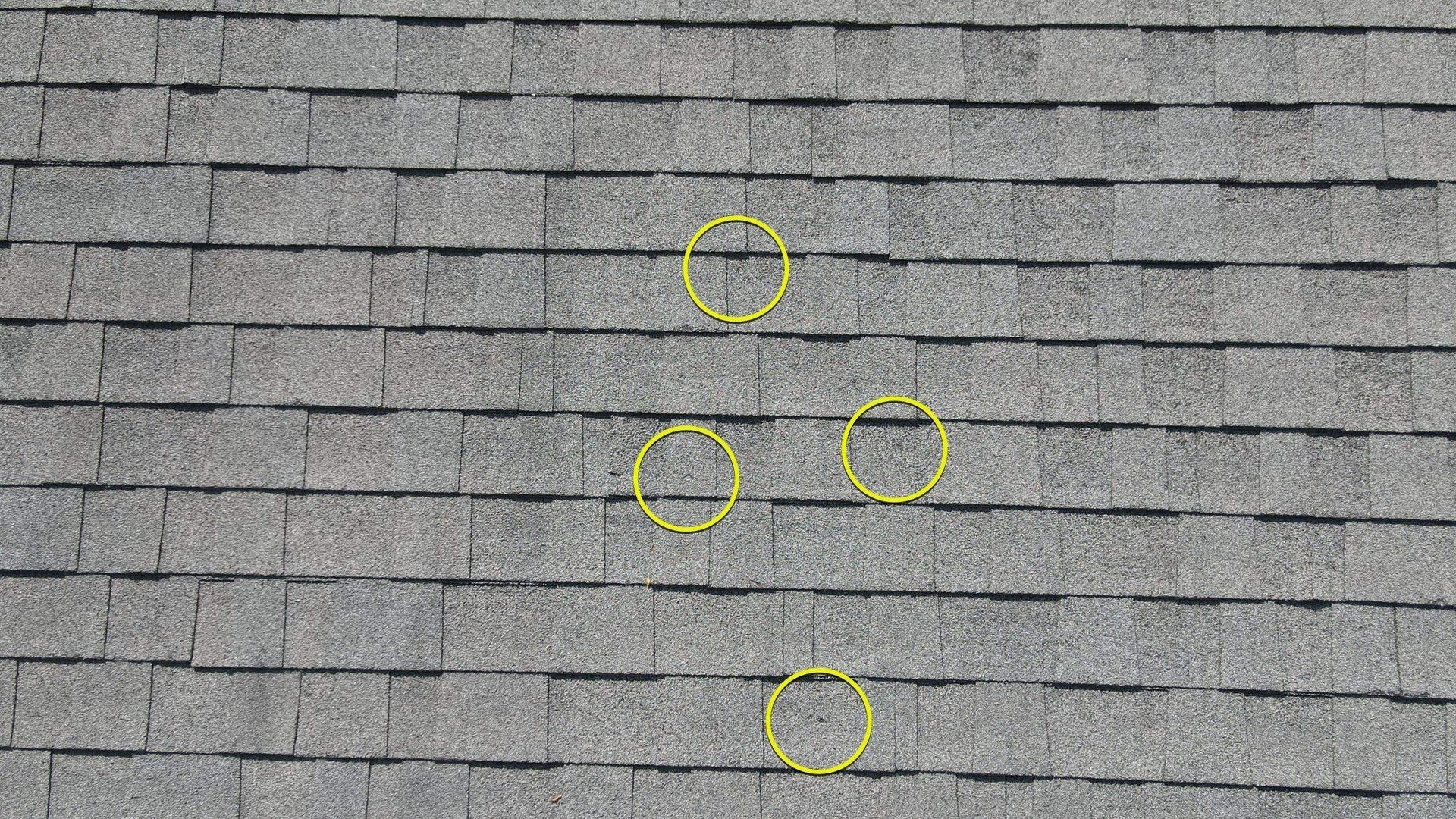 Image of roof during hail damage inspection by RETEX's Mark Erickson, with added yellow circles highlighting damaged areas.